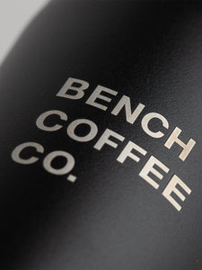 Detail shot of Made by Fressko reusable cup, with BENCH COFFEE CO. logo, in black